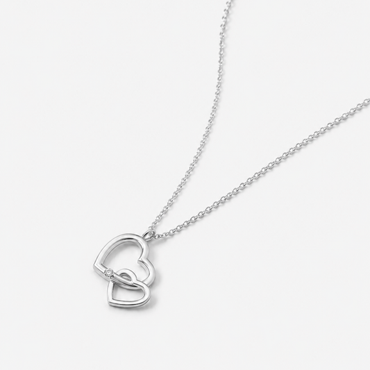 Silver necklace with a heart-shaped pendant on a light gray background