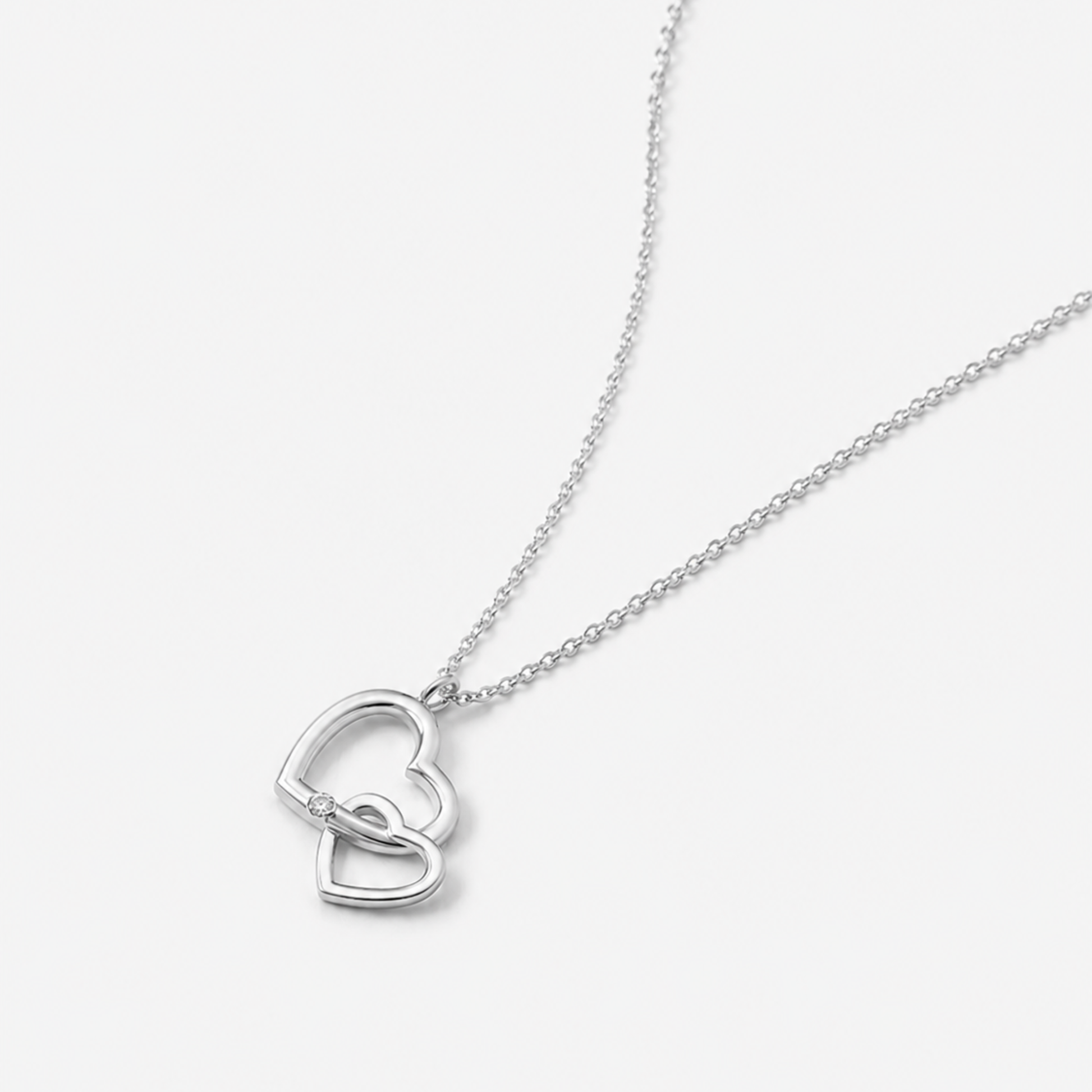 Silver necklace with a heart-shaped pendant on a light gray background